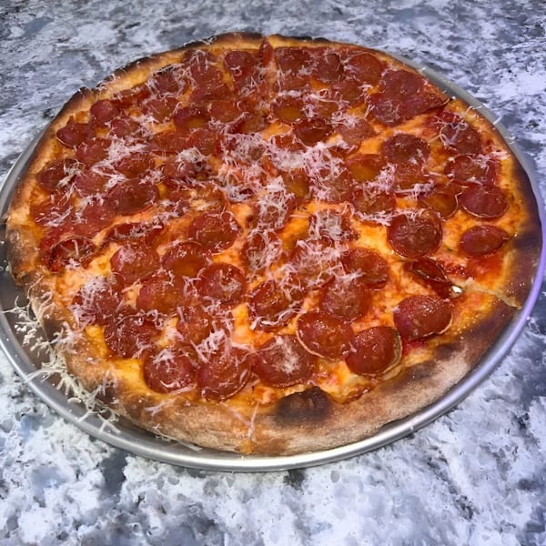 PZZA Boca Raton's pepperoni pizza, topped with shredded parmesan, on a metal pan.