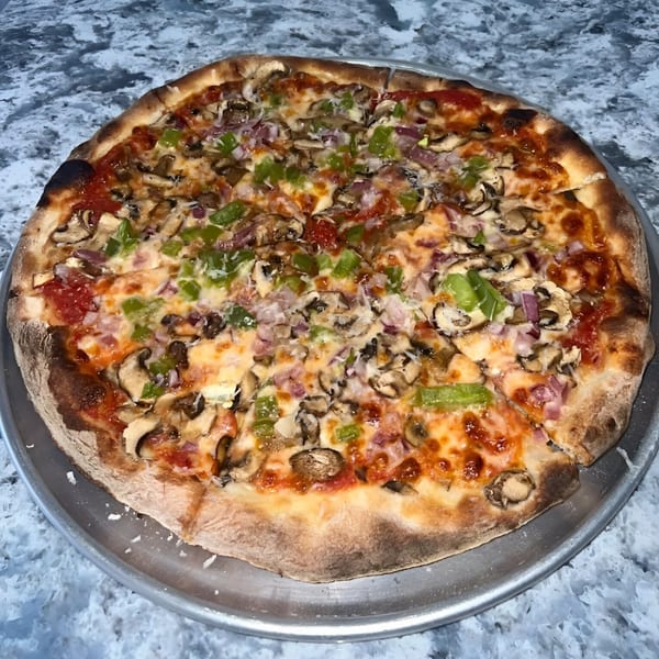 A whole PZZA pizza with mushrooms, green peppers, and ham on a metal tray.